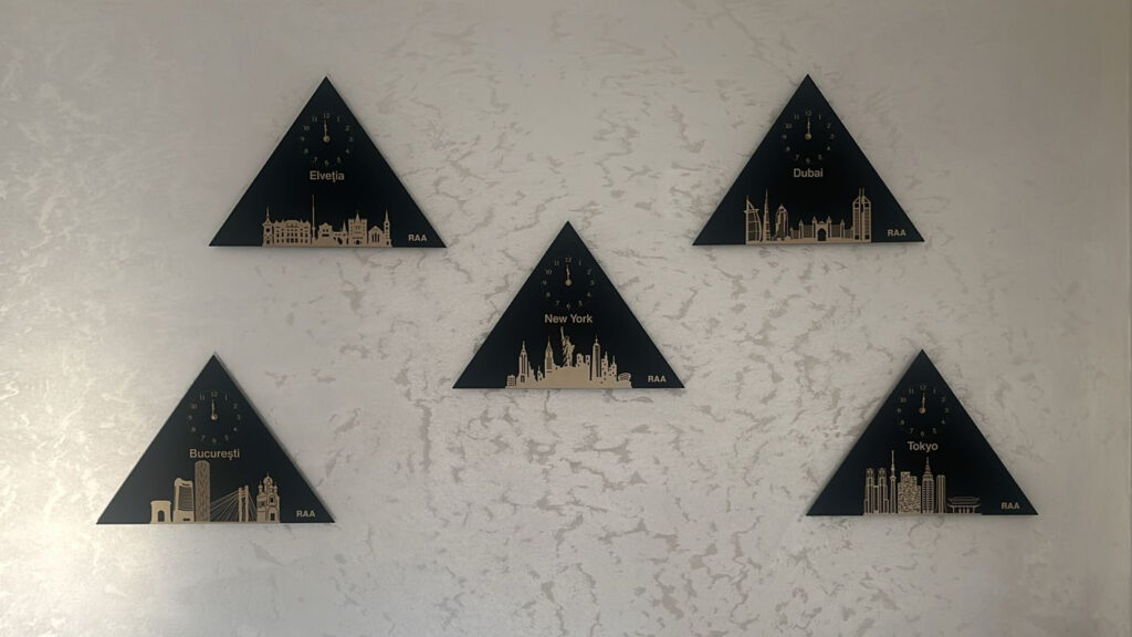 Colecție exclusivistă de cinci ceasuri triunghiulare personalizate reprezentând New York, Tokyo, Elveția, București și Dubai în aranjament geometric pe perete marmorat